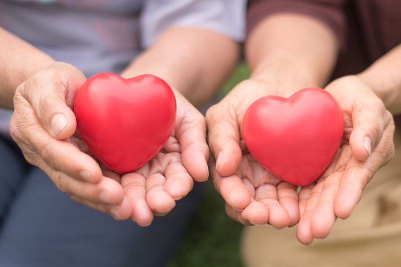 Two pairs of hands each holding a red heart