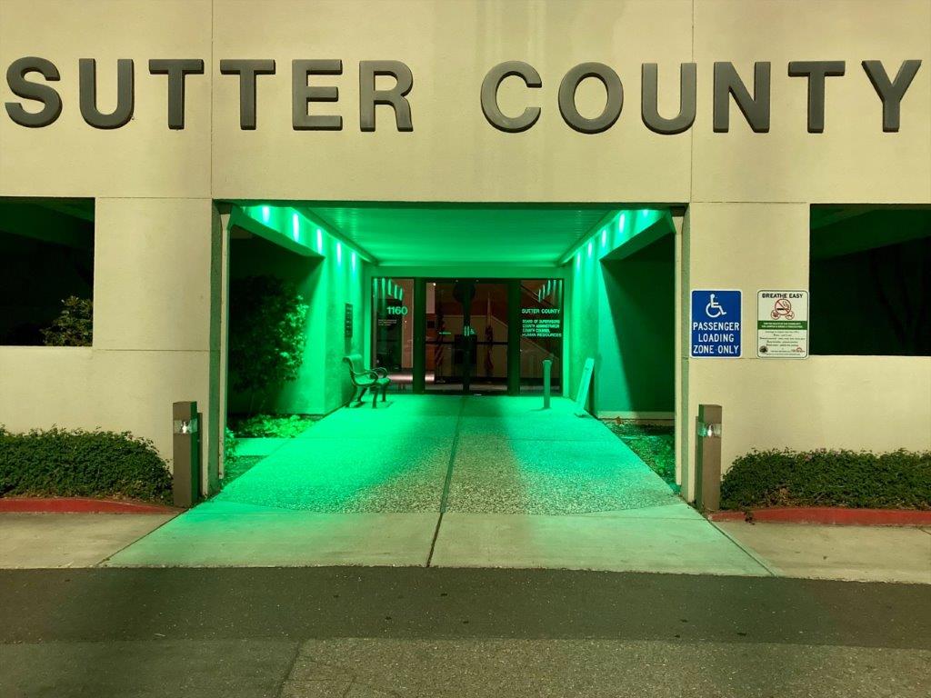 County office exterior lit by green lights.